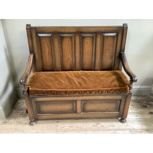 449 - An oak veneered settle having four field panels to the back, squab cushion, lift up lid to the box w... 