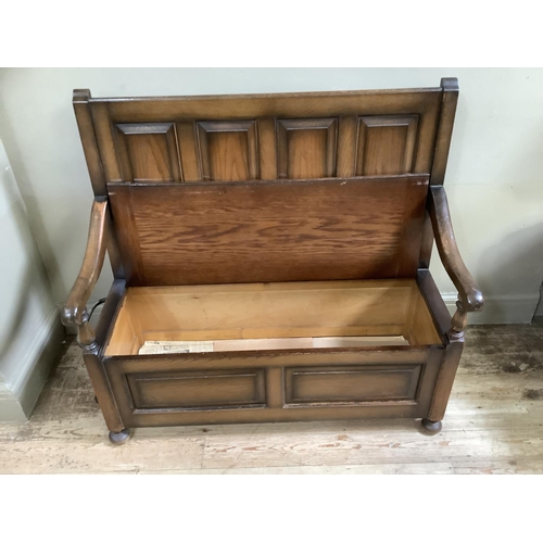 449 - An oak veneered settle having four field panels to the back, squab cushion, lift up lid to the box w... 