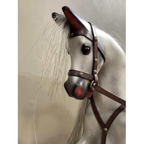 453 - A reproduction rocking horse, grey dappled with red leather saddle and on a red bow base