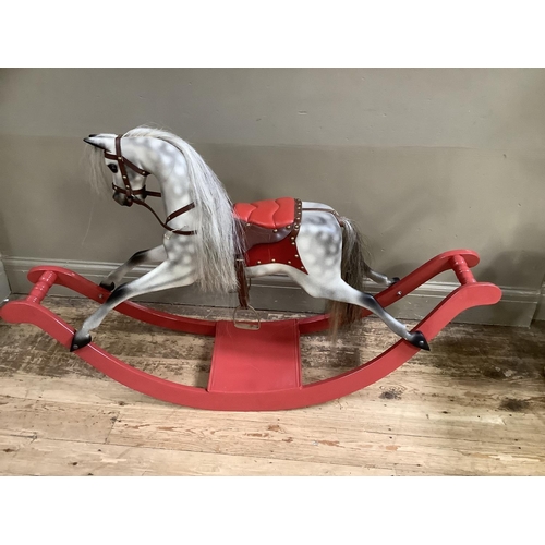 453 - A reproduction rocking horse, grey dappled with red leather saddle and on a red bow base