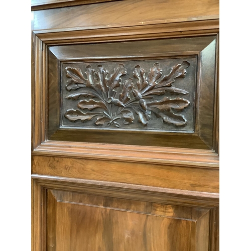 405 - A late Victorian walnut wardrobe having an arch pediment, above a mirror door to the centre flanked ... 