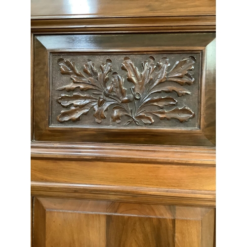 405 - A late Victorian walnut wardrobe having an arch pediment, above a mirror door to the centre flanked ... 