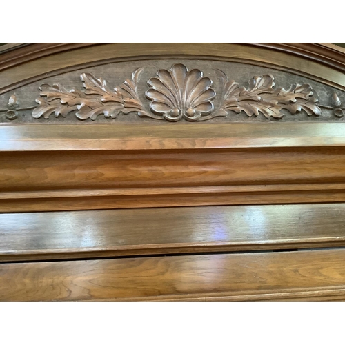 405 - A late Victorian walnut wardrobe having an arch pediment, above a mirror door to the centre flanked ... 