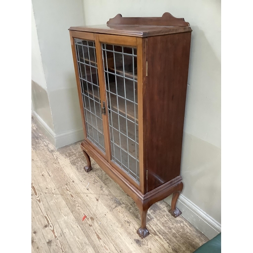 415 - A 1930s walnut and leaded glass two door bookcase having a short raised back above two doors, interi... 