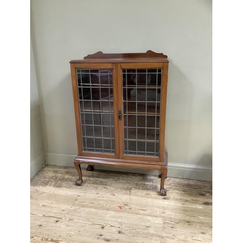 415 - A 1930s walnut and leaded glass two door bookcase having a short raised back above two doors, interi... 