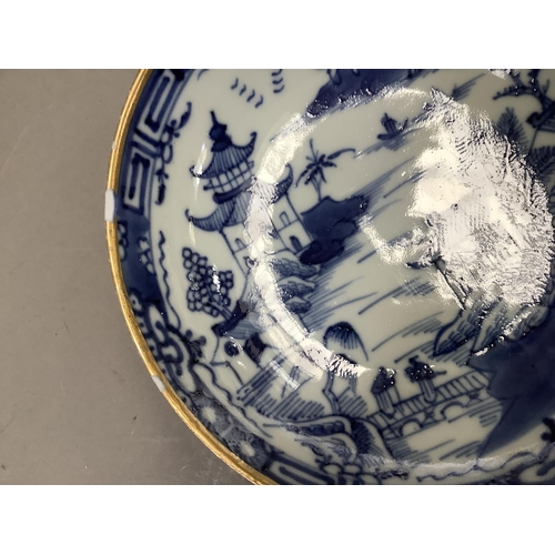 17 - A Chinese export blue and white cup and saucer painted with the willow pattern with gilt highlights ... 