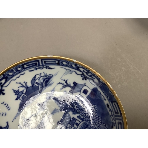 17 - A Chinese export blue and white cup and saucer painted with the willow pattern with gilt highlights ... 