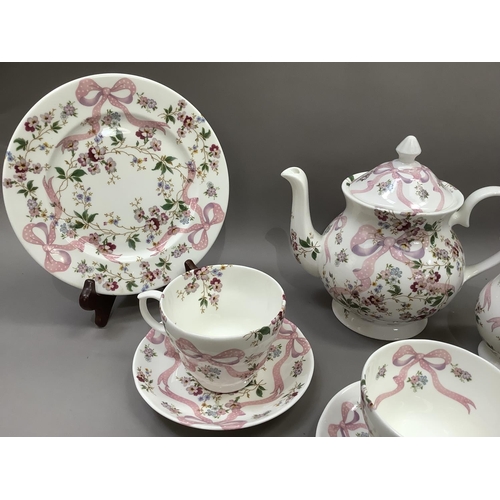 26 - A china part service printed in pink, blue, mauve and green with a ribbon and floral sprays design c... 