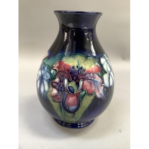 31b - A Moorcroft pottery vase of iris pattern, tube lined and painted in mauve and green on a blue ground... 