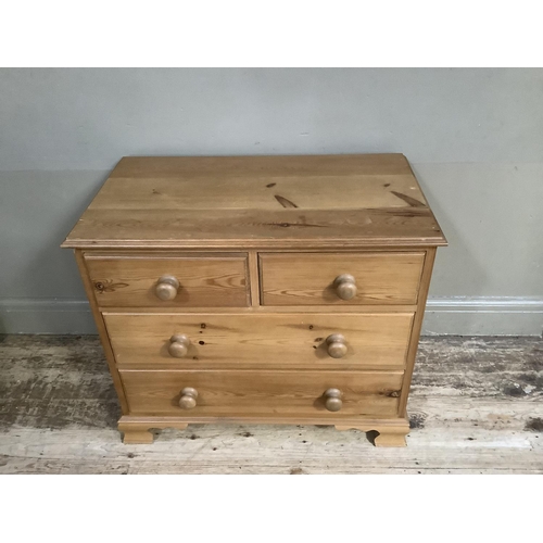 77 - A modern pine chest of two short and two long drawers with turned handles, on shaped ogee bracket fe... 