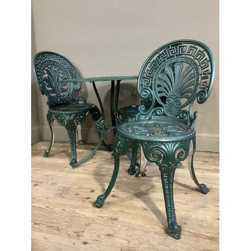 321 - A patio table of circular outline and pierced foliate design together with three green metal chairs ... 