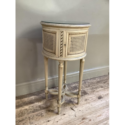 332 - A French style cream bergere caned drum bedside cabinet with mirrored top on fluted legs joined by a... 