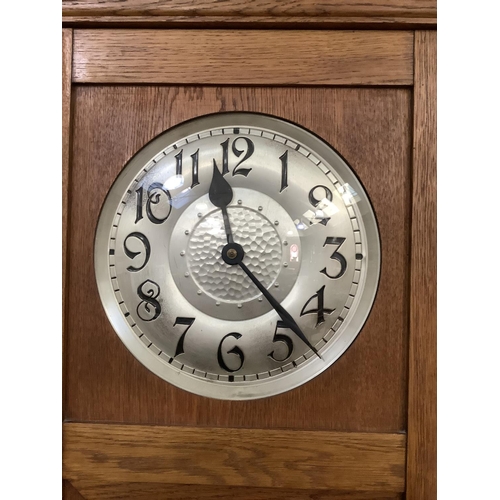 345 - A 1930s oak and glazed longcase clock having a silvered dial with black Arabic numerals above a glaz... 