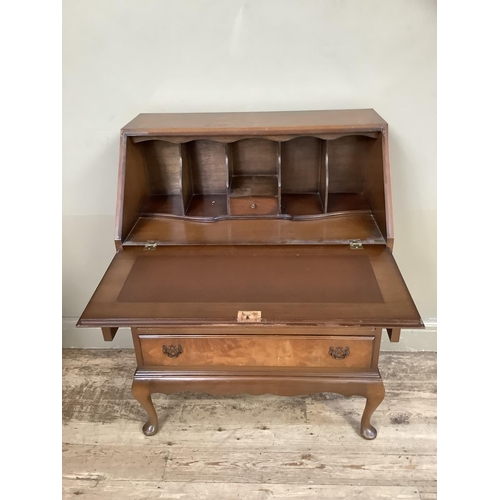 348 - A reproduction walnut bureau having a fall front with fitted interior over three drawers and on cabr... 