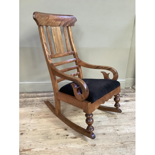 359 - A 19th century satin beech rocking chair with black upholstered seat