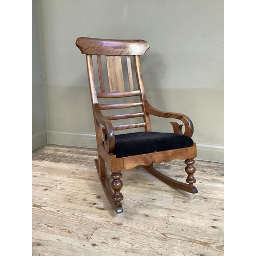 359 - A 19th century satin beech rocking chair with black upholstered seat