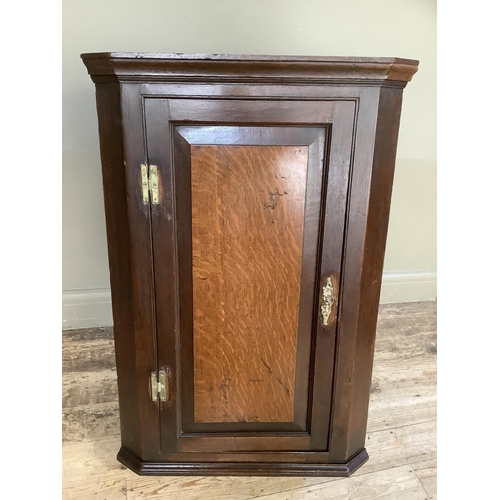 362 - A 19th century oak corner hanging cupboard having a panel indented door with H brass hinges and cant... 