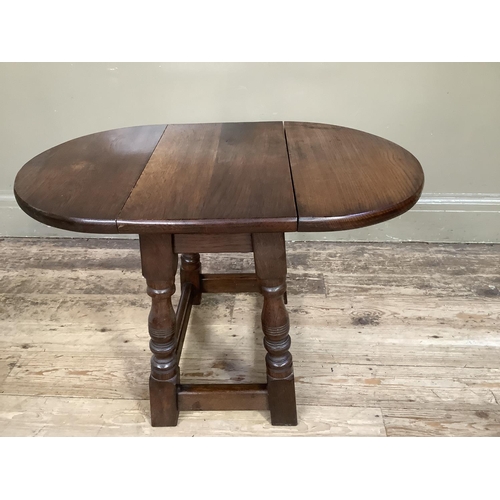 380 - An oak oval occasional drop leaf table on baluster turned and square framing