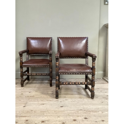 383 - A pair of oak open armchairs, brown hide upholstered with close nailing on turned and square framing