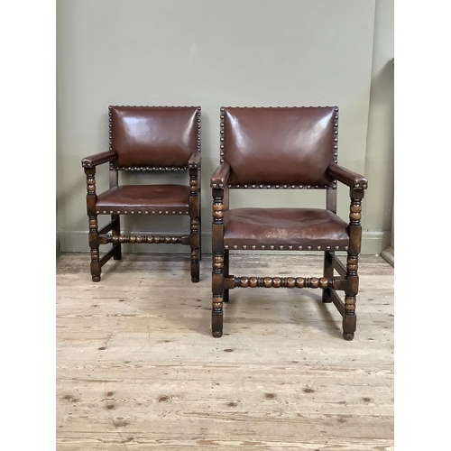 383 - A pair of oak open armchairs, brown hide upholstered with close nailing on turned and square framing