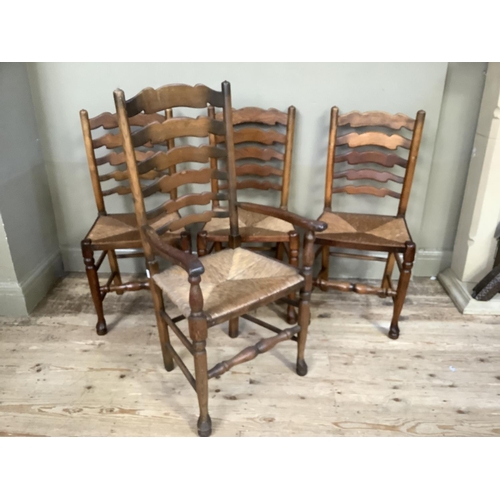 384 - A set of four wavy ladderback, rush seated dining chairs, carver and three singles