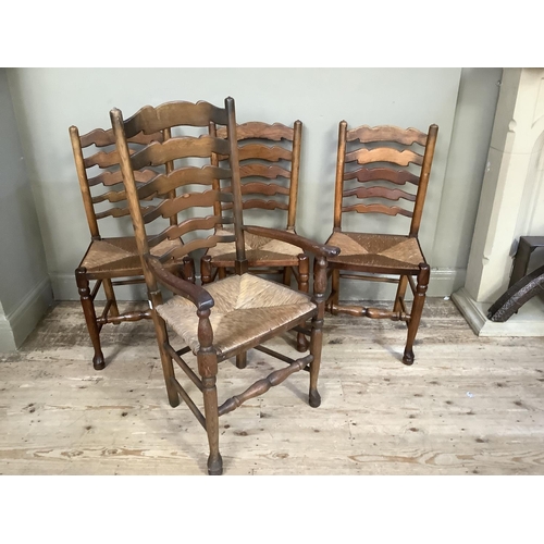 384 - A set of four wavy ladderback, rush seated dining chairs, carver and three singles