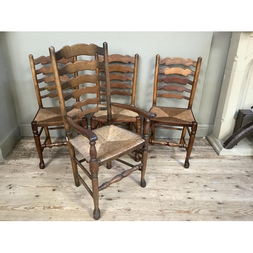 384 - A set of four wavy ladderback, rush seated dining chairs, carver and three singles