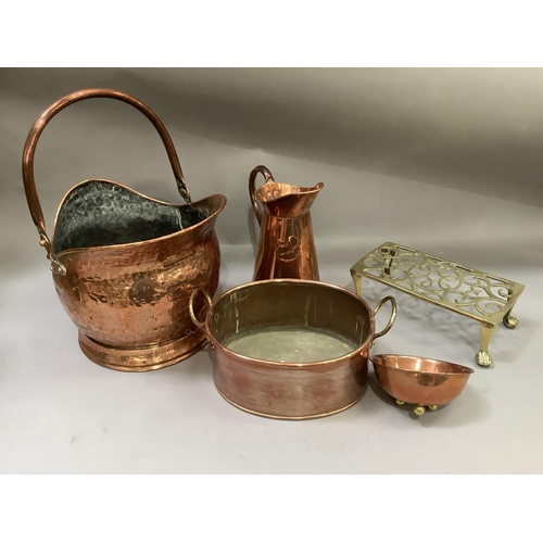 138 - A copper coal scuttle, copper jug, planter, bowl on three feet and a brass trivet