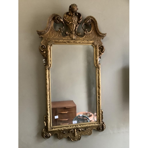 320 - A gilt wall mirror of mid 18th century design having broken pediment and foliate shell cresting with... 