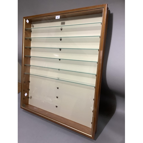 88 - A glazed wall mounted display cabinet of narrow proportions with glass shelves, 76cm wide x 9cm deep... 