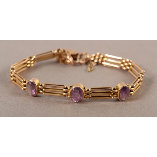 411 - AN EDWARD VII AMETHYST SET GATE BRACELET in 9ct rose gold, the oval faceted stones collect set and i... 