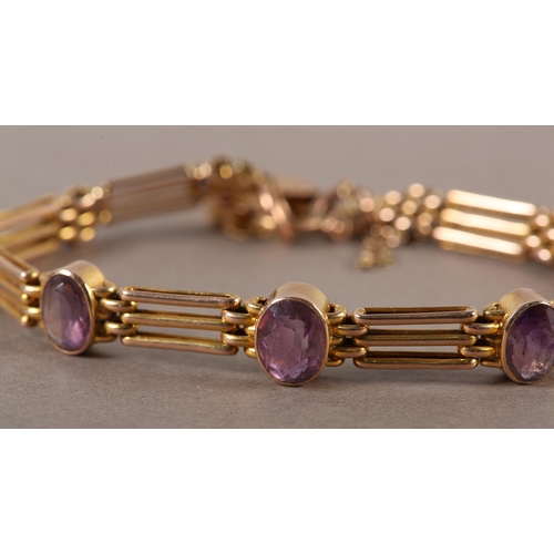 411 - AN EDWARD VII AMETHYST SET GATE BRACELET in 9ct rose gold, the oval faceted stones collect set and i... 