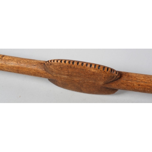 49 - A HARDWOOD STAFF, having a T shaped head, the shaft carved with a serrated and flattened oblong, lat... 