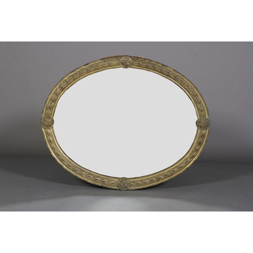 569 - A LATE 19TH CENTURY GILT METAL FRAMED OVAL WALL MIRROR, the frame embossed with band of harebells wi... 