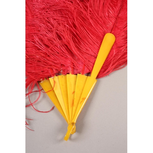 107 - A shaded cerise ostrich feather fan, 1920’s the curled feathers mounted on butterscotch yellow plast... 