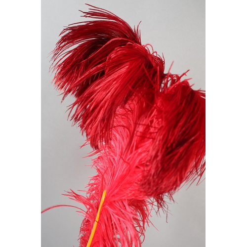 107 - A shaded cerise ostrich feather fan, 1920’s the curled feathers mounted on butterscotch yellow plast... 