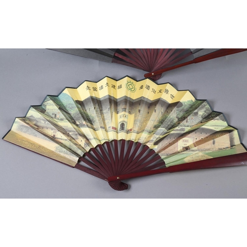 46 - Two large, good quality, folding fans, both printed on silk, on wood montures, one showing buildings... 