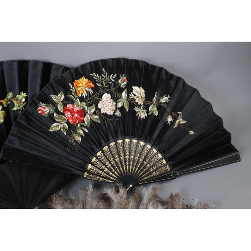 47 - Three large, late 19th century black wood fans, the first with a black satin leaf profusely embroide... 