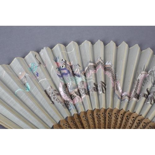 58 - A 20th century Chinese carved sandalwood fan, the white cotton gauze leaf embroidered in pastel silk... 