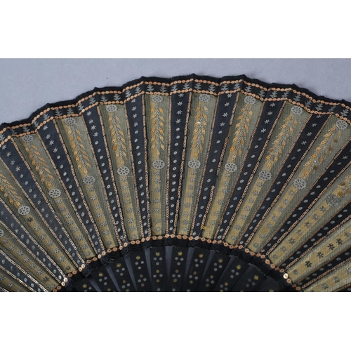 74 - A good and fairly large sequined fan, c 1900, the gold lamé leaf overlaid on alternate folds with bl... 