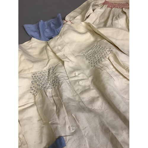 265 - Two cream silk children’s dresses, with smocking; a pair of boy’s short trousers; together with baby... 