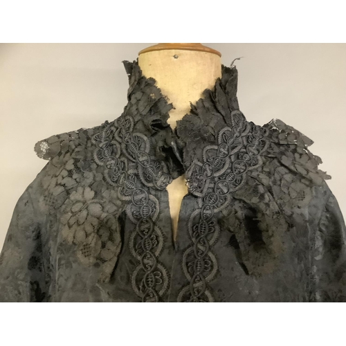 337 - A black embossed silk late Victorian cape, three-quarter length, trimmed with black machine lace and... 