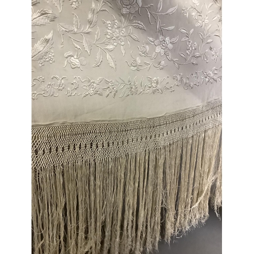 347 - An embroidered silk Canton shawl, cream on cream, with macramé fringe, each corner with a large flor... 