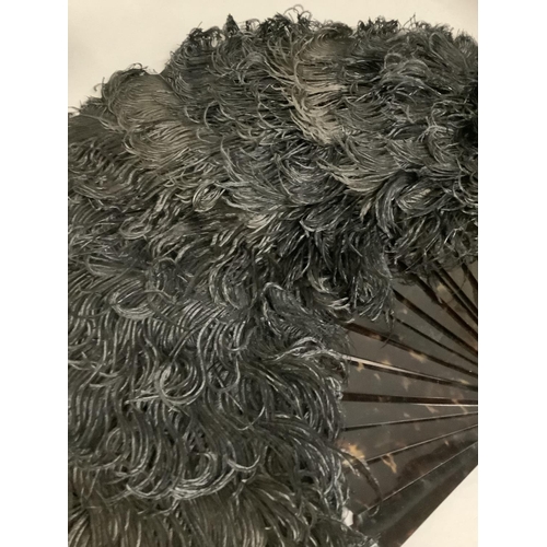 99 - A large black ostrich feather fan, the monture of tortoiseshell, the upper guard fitted with a detac... 