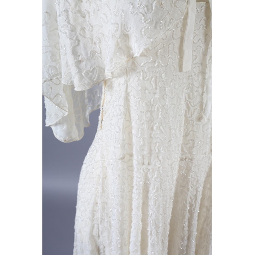 360 - A cream 1920’s chiffon wedding dress and shoulder cape, decorated with clear beads, the dress sleeve... 