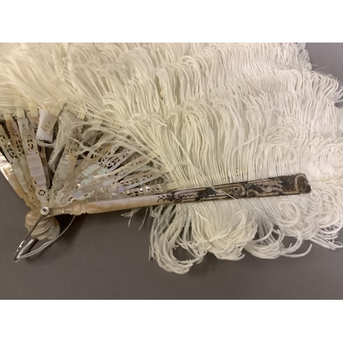 104 - An attractive white ostrich feather fan, being mounted on pink mother of pearl the sticks carved, sh... 