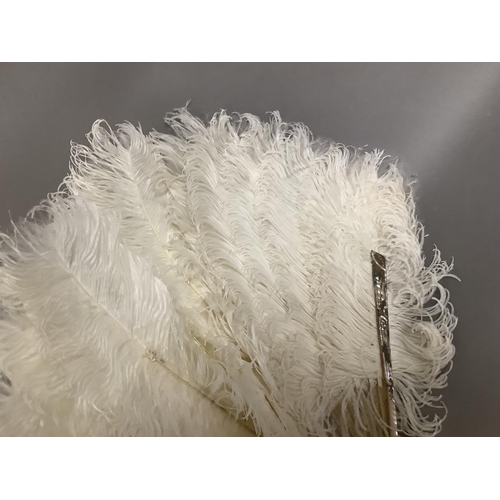 104 - An attractive white ostrich feather fan, being mounted on pink mother of pearl the sticks carved, sh... 