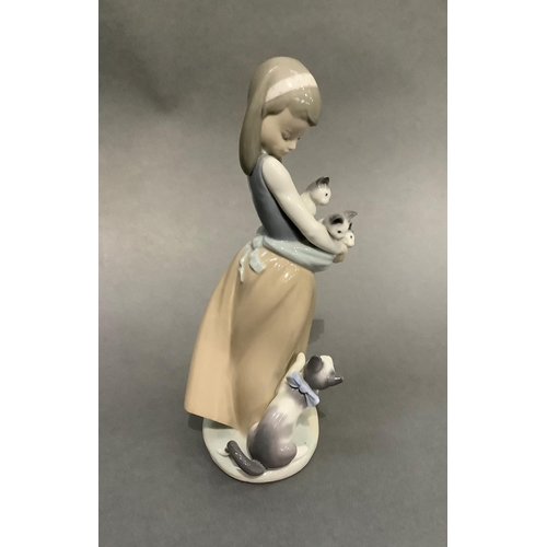 15 - A Lladro figure of a girl holding kittens in her apron, a cat at her feet, 25cm high