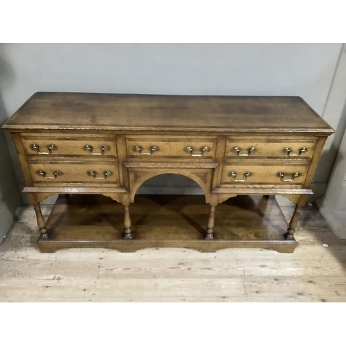 343 - A good oak crossbanded dresser base having a drawer to the centre above an arched apron and two grad... 