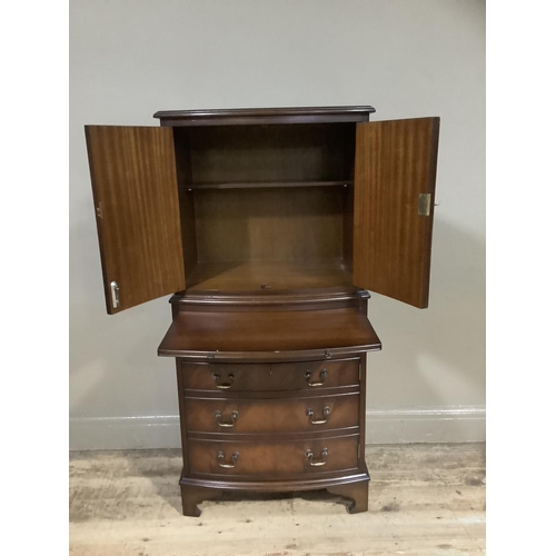 360 - A reproduction mahogany drinks cabinet, bow fronted, having two drawers above a pull slide and four ... 